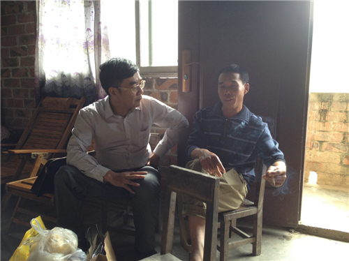 图为自治区残联副理事长许健强与结对帮扶贫困户亲切交谈