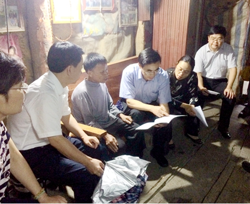 图为调研组在田东县作登瑶族乡贫困残疾人家里查看扶贫手册